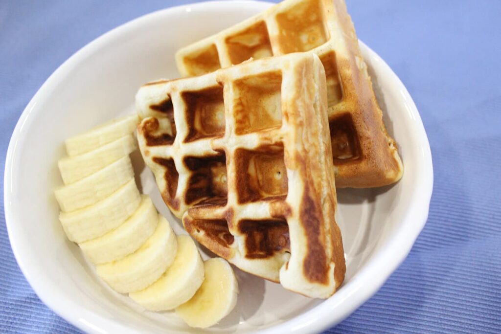 Presentation of a stacked serving of prepared warm waffles.
