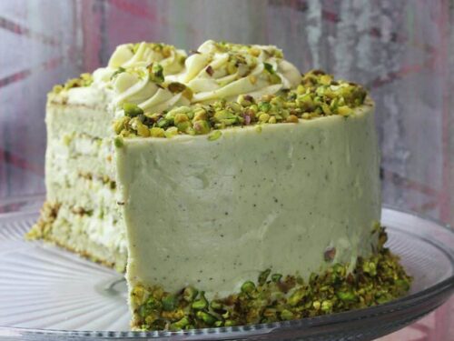 Vertical format photograph highlighting the complete pistachio cake structure.