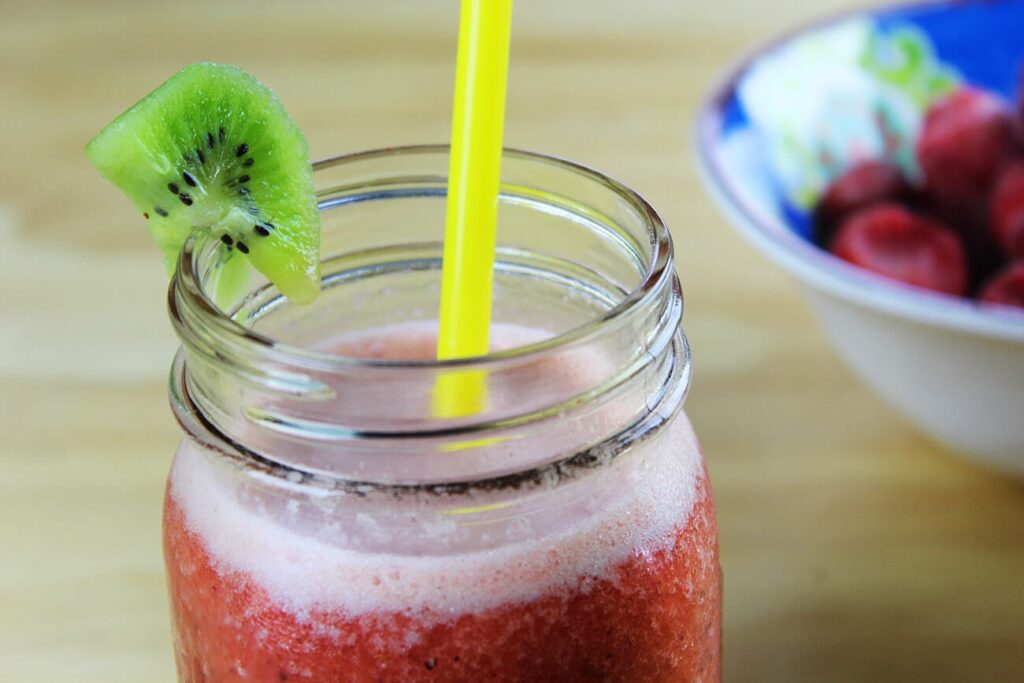 Side perspective displaying the full height of a served glass of strawberry kiwi smoothie.