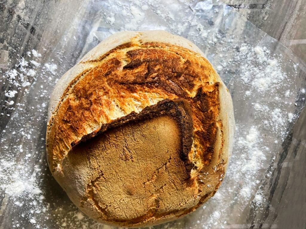 Overhead view showing the flour dusted scored top crust of the finished dutch oven bread.