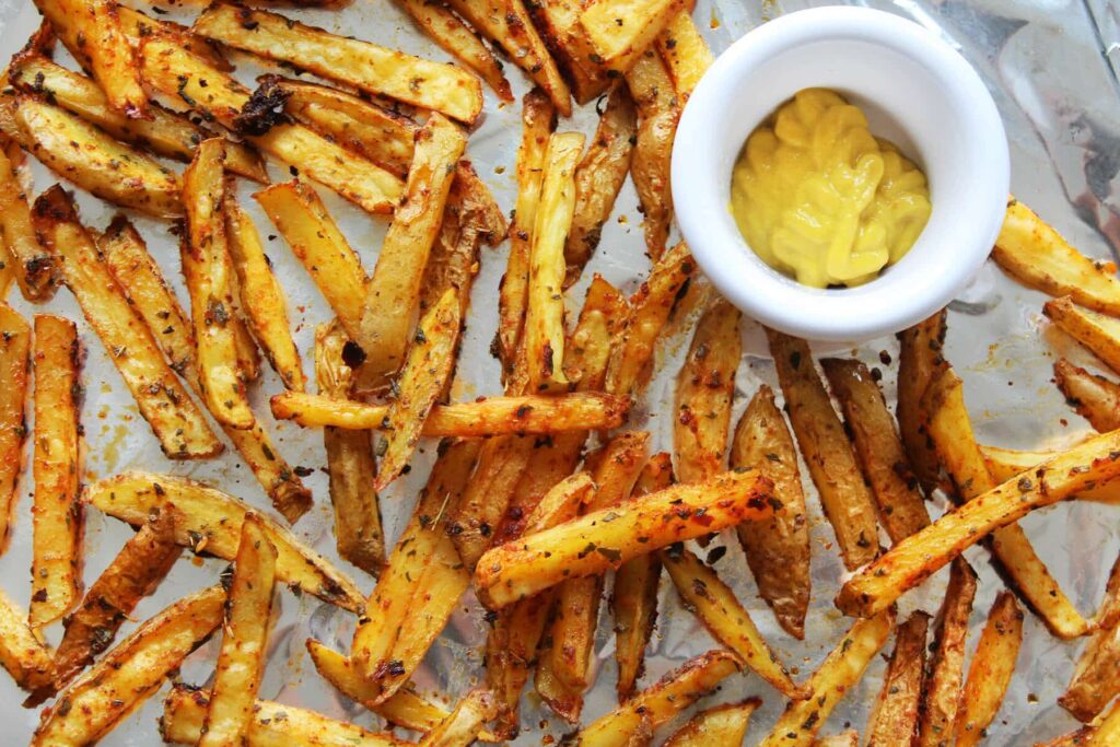 Overhead view showing the scattered layout of the finished spicy baked french fries batch.