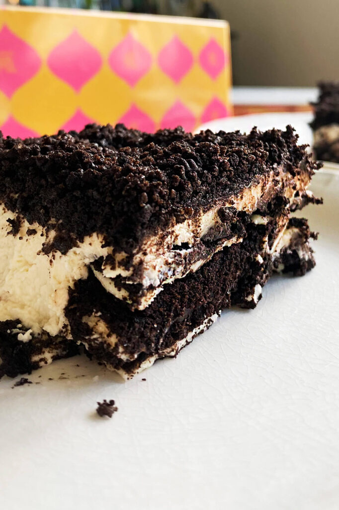 Vertical format photograph showcasing a single sliced piece of the chilled oreo ice box cake.