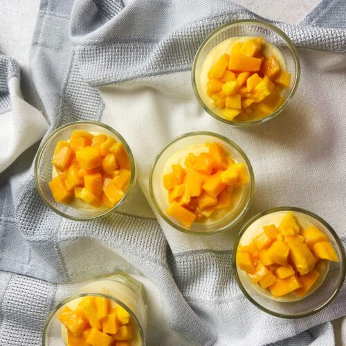 Overhead view looking down into the bright yellow surface of the prepared mango mousse cup.