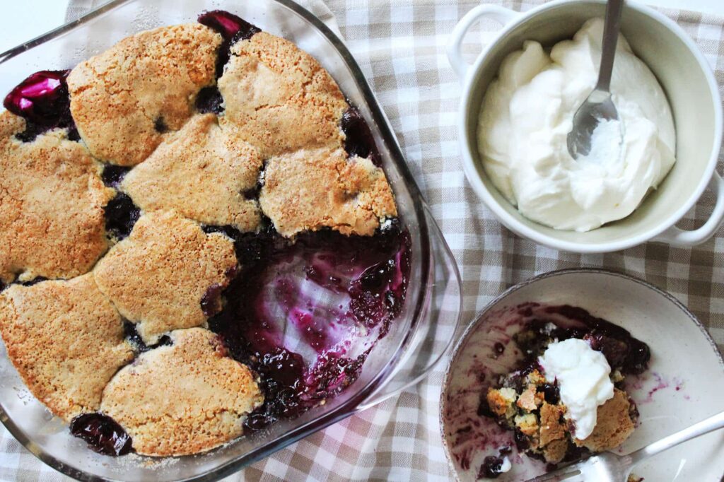 Overhead view displaying the rustic golden brown top coverage of the finished blueberry cobbler pan.