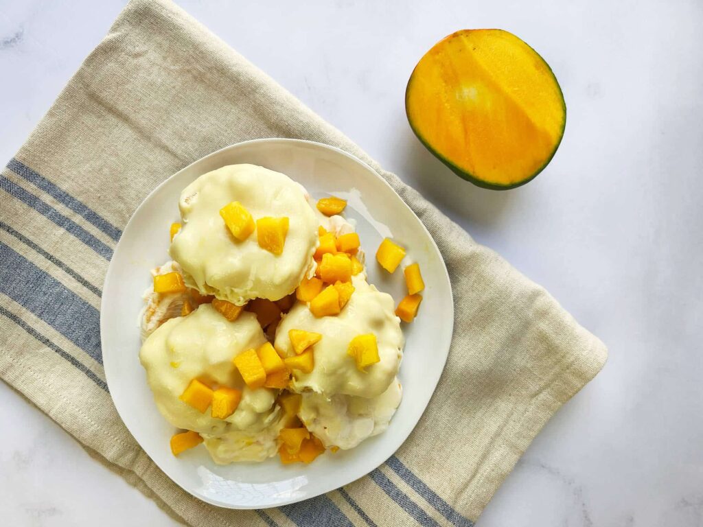 Vista desde arriba (plano cenital) de la bandeja con snacks de mango con yogurt ordenados.