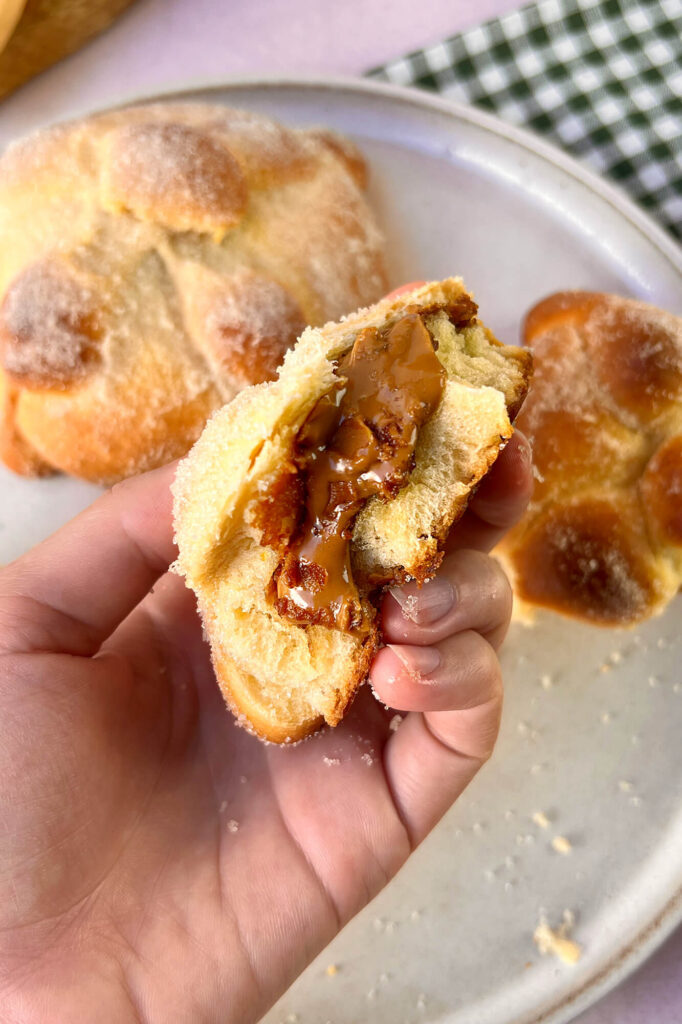 Toma cercana enfocada en la textura espolvoreada de azúcar del pan de muerto relleno.