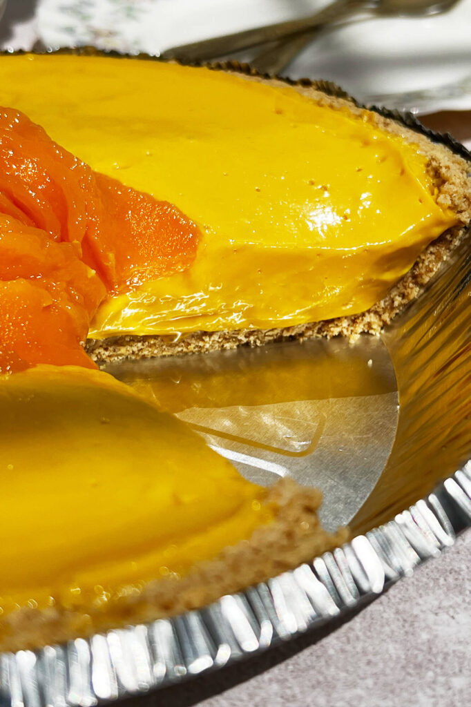 Fotografía en formato vertical que muestra una porción de pay de mango sin horno.